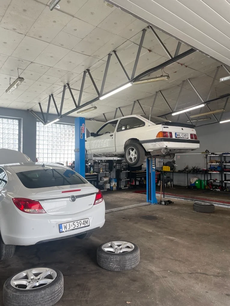 Samochód na podnośniku w warsztacie Twin Torque Service w Warszawie – mechanik przygotowuje się do naprawy zawieszenia.